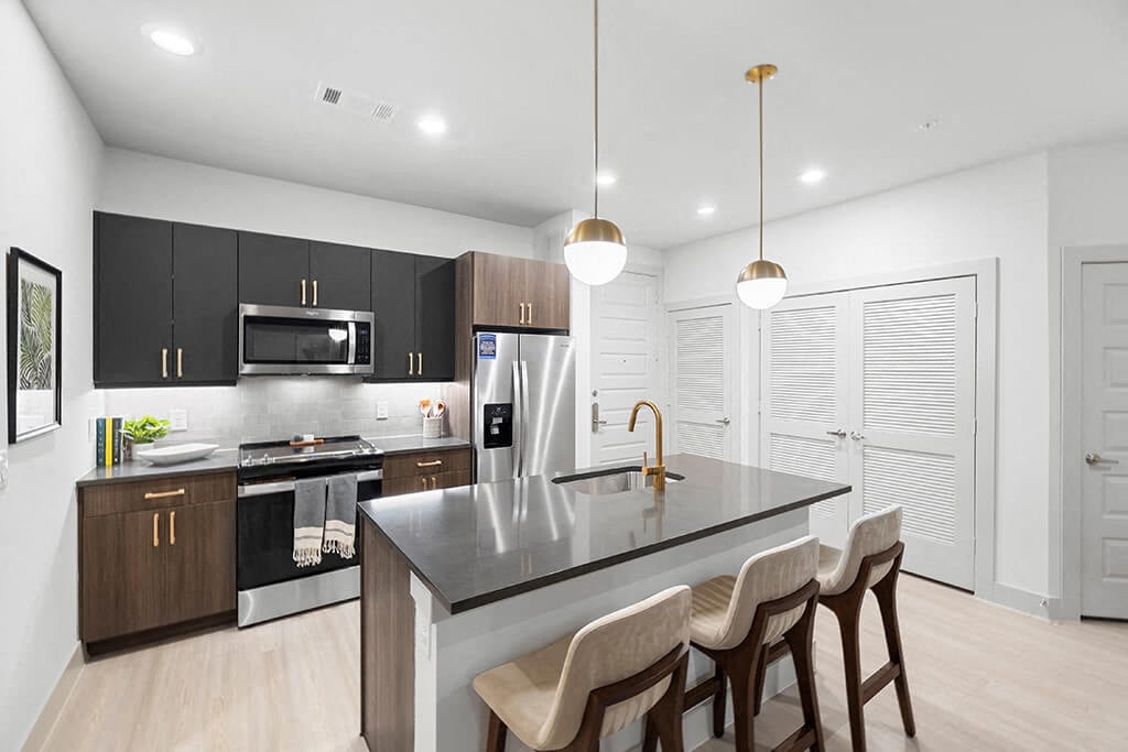 A bright, modern kitchen with dark counters and a kitchen island at the East Bend Apartments in Houston, Texas.